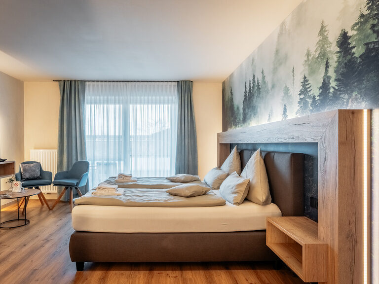 Exklusives Doppelzimmer: Komfort trifft auf Stil Ein großes Bett mit Fernseher im Doppelzimmer Deluxe mit Gemeinschaftsgarten.